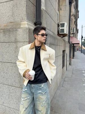 Male model wearing ivory contrast corduroy collar jacket with black t-shirt and distressed wide-leg jeans on urban street