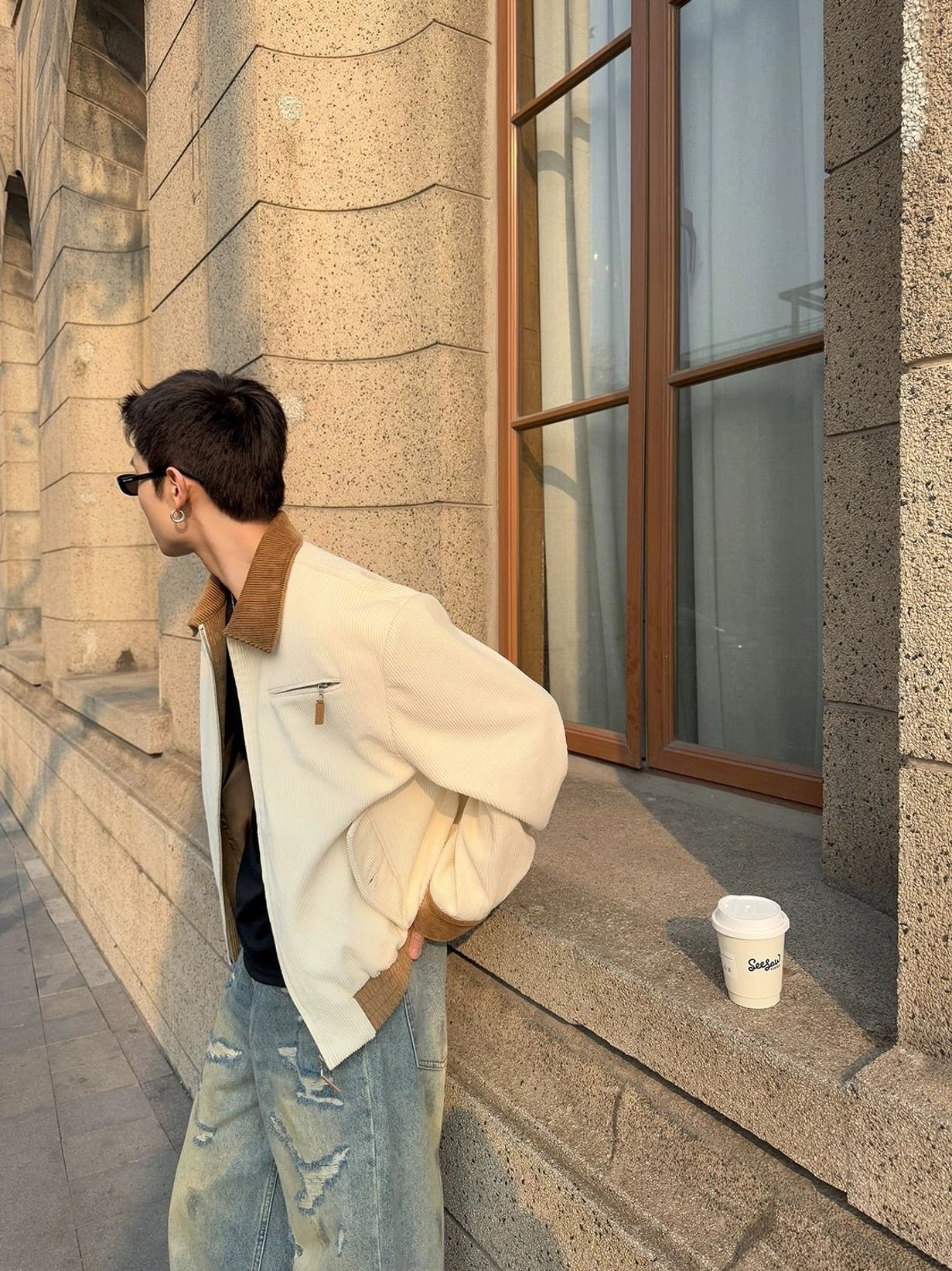 Side profile of apricot ivory jacket with brown corduroy collar cuffs and zip chest pocket in vintage urban setting