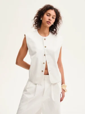 Close-up view of ivory cropped sleeveless cotton vest with front buttons and relaxed boxy fit