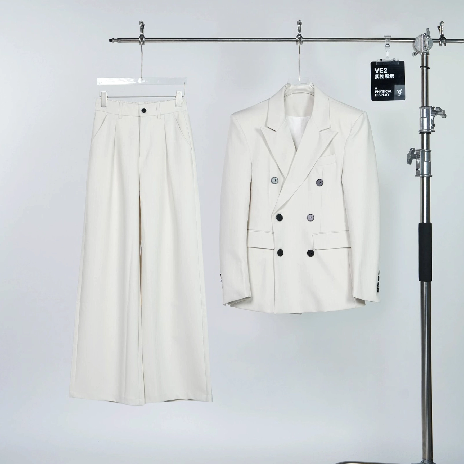 Ivory double-breasted blazer and pleated wide-leg trousers two-piece suit set displayed on clothing rack