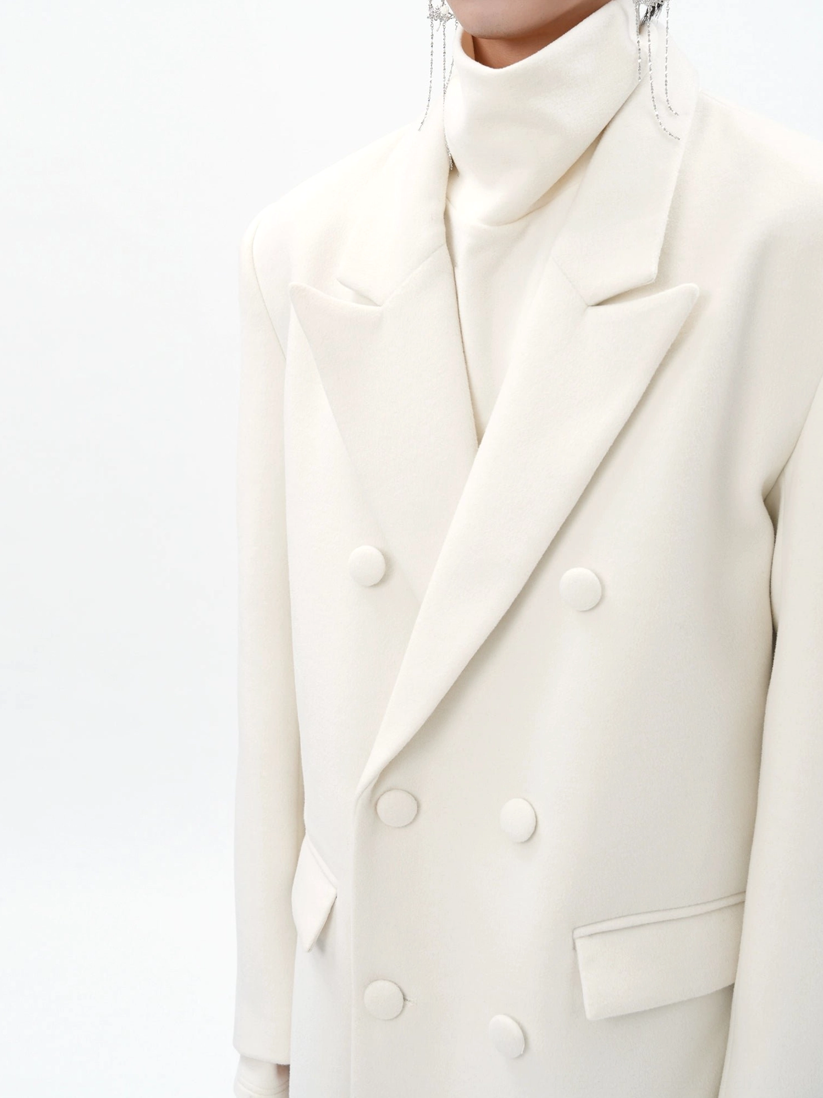 Close-up of men's ivory double-breasted wool blend overcoat showing wide notch lapel buttons and flap pockets