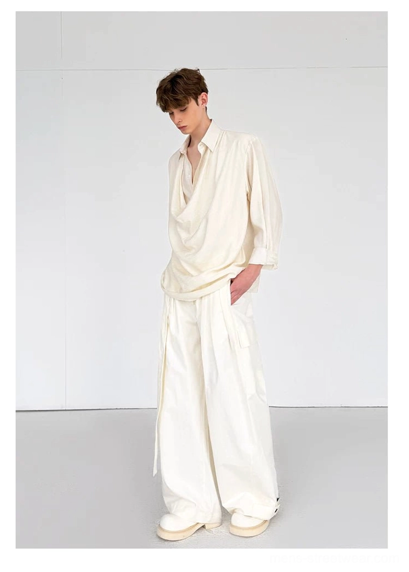 Side view of men's draped ivory shirt styled with loose wide-leg trousers for an avant-garde streetwear look
