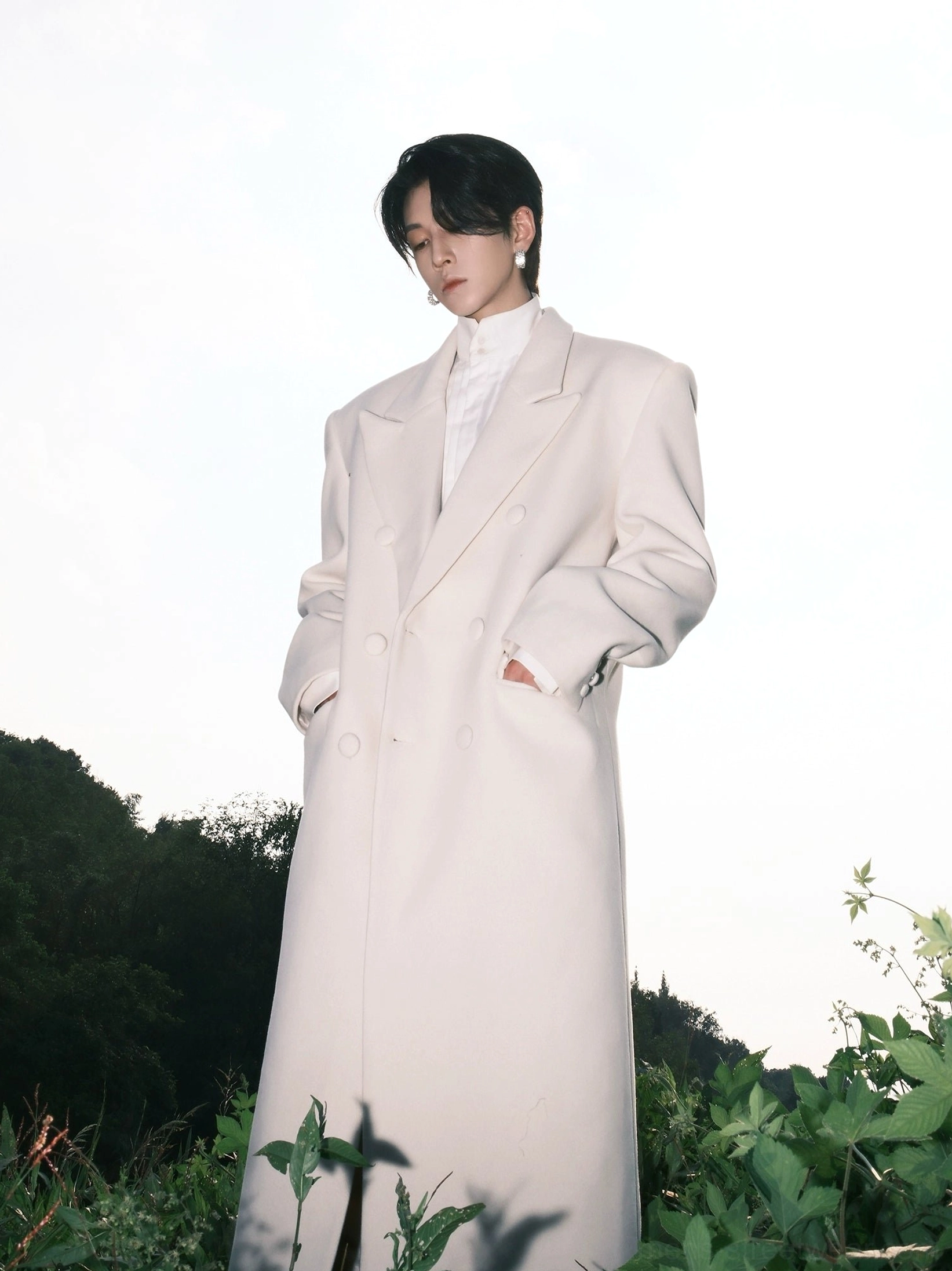 Men's ivory Korean streetwear wool blend overcoat with long relaxed silhouette shown from the right side outdoors