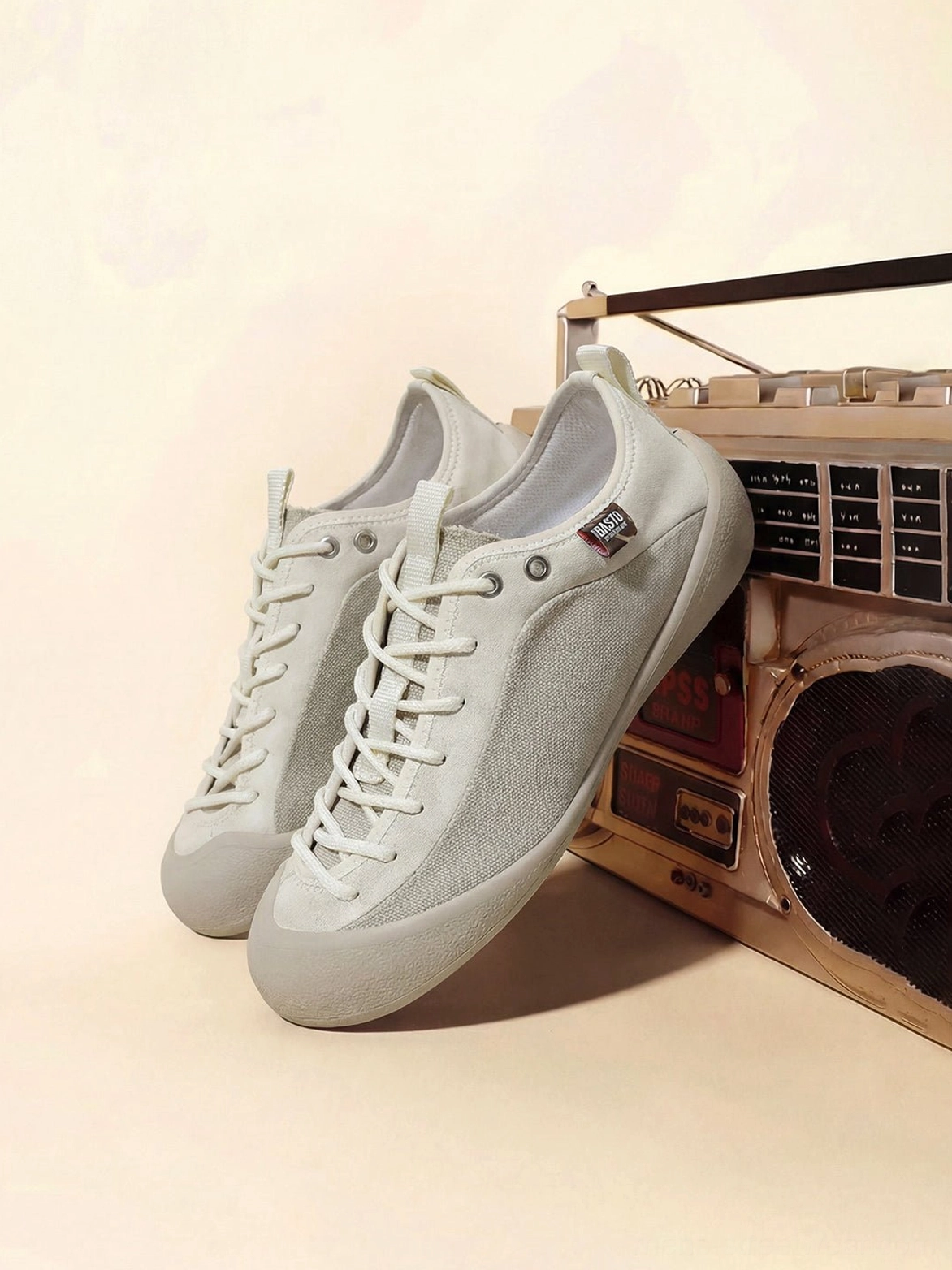 Front three-quarter view of ivory low-top streetwear sneakers featuring suede-textured accent panels, clean laces, and a slim rubber outsole
