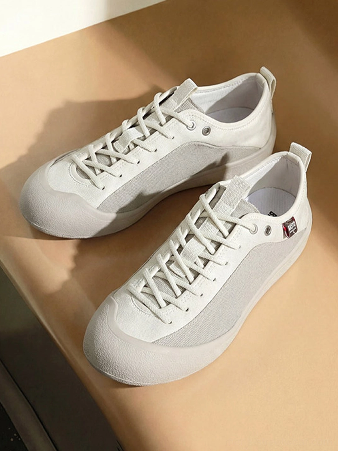 Angled overhead view of ivory mesh and canvas sneakers with woven flat laces, textured toe caps, and neutral Korean streetwear styling