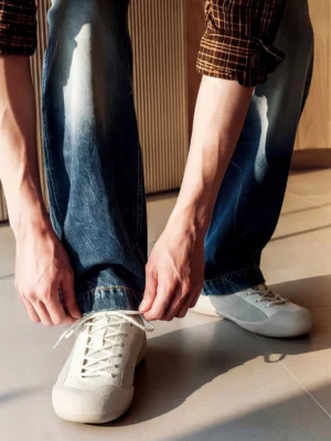 Male model wearing ivory mesh-panel low-top sneakers with blue jeans in a casual Korean streetwear outfit