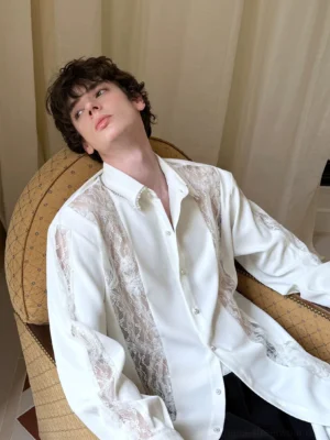 Close view of men's ivory oversized longline shirt with sheer floral lace panels and pearl-style collar detail