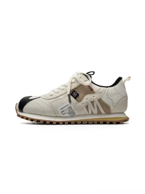 Ivory retro runner sneakers with black toe accents, layered panels, exposed stitching, and gum waffle outsole shown in side profile