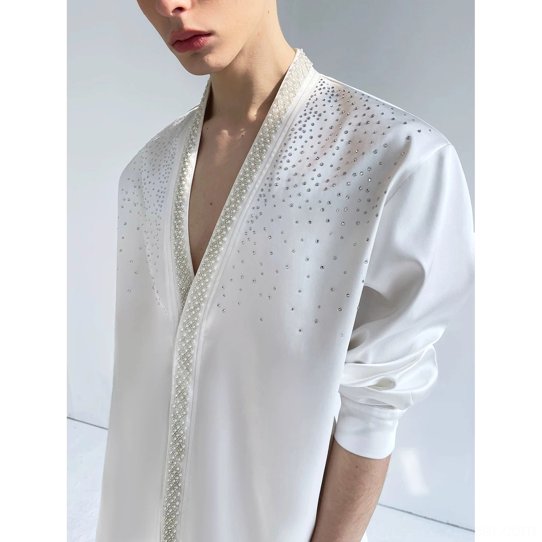 Close-up of the ivory satin shirt's delicate pearl-style beaded placket, scattered crystal accents, and smooth reflective fabric texture