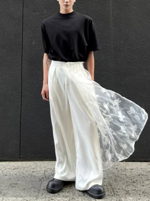 Front view of ivory satin wide-leg trousers with floral embroidered sheer train worn with a black t-shirt