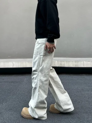 Side view of ivory baggy utility cargo pants with large flap pocket seam details and wide leg streetwear fit