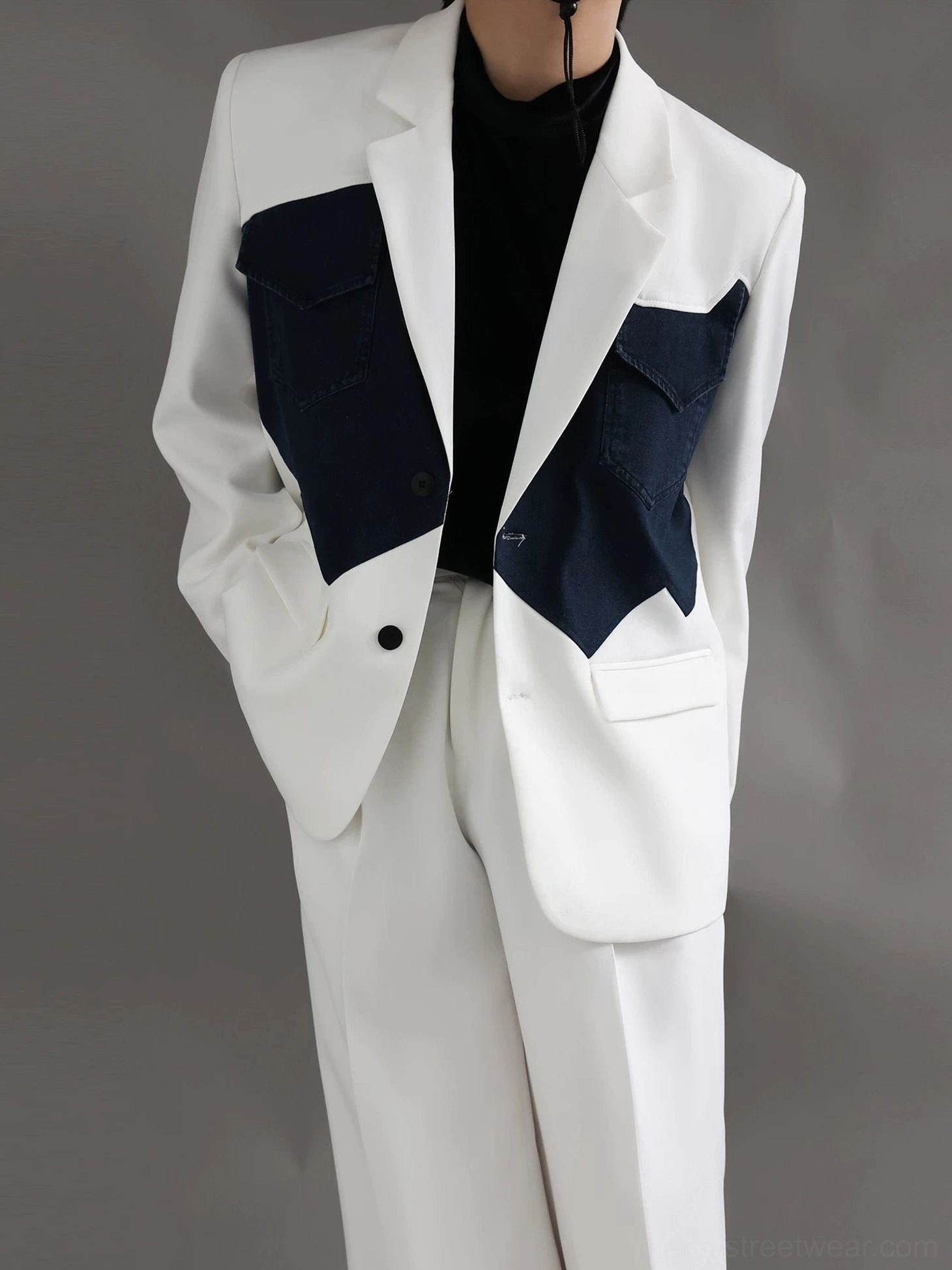 Front detail of an ivory color-block Western blazer with jagged dark navy chest pockets, notched lapels, and single-button closure