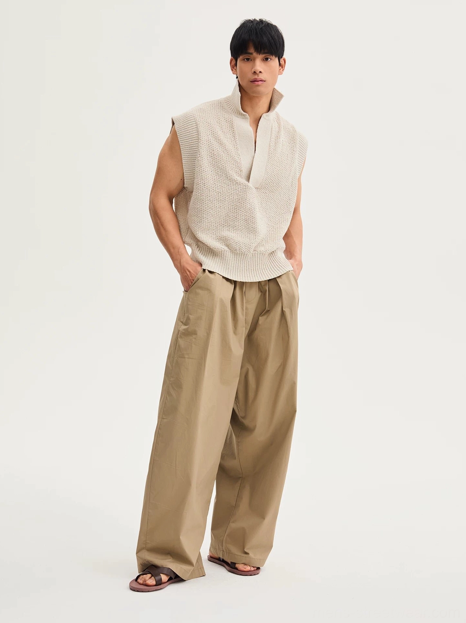 Khaki wide-leg cotton pants shown from a side-front view with relaxed curved cut, elastic drawstring waist, and off-white sleeveless knit styling