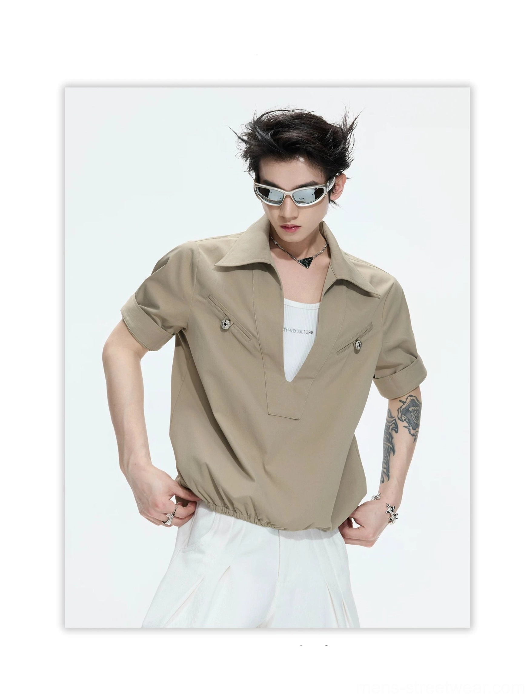 Khaki deep V-neck utility shirt with rolled short sleeves, metallic chest pocket buttons, pointed collar, gathered hem, and Korean streetwear styling on a male model