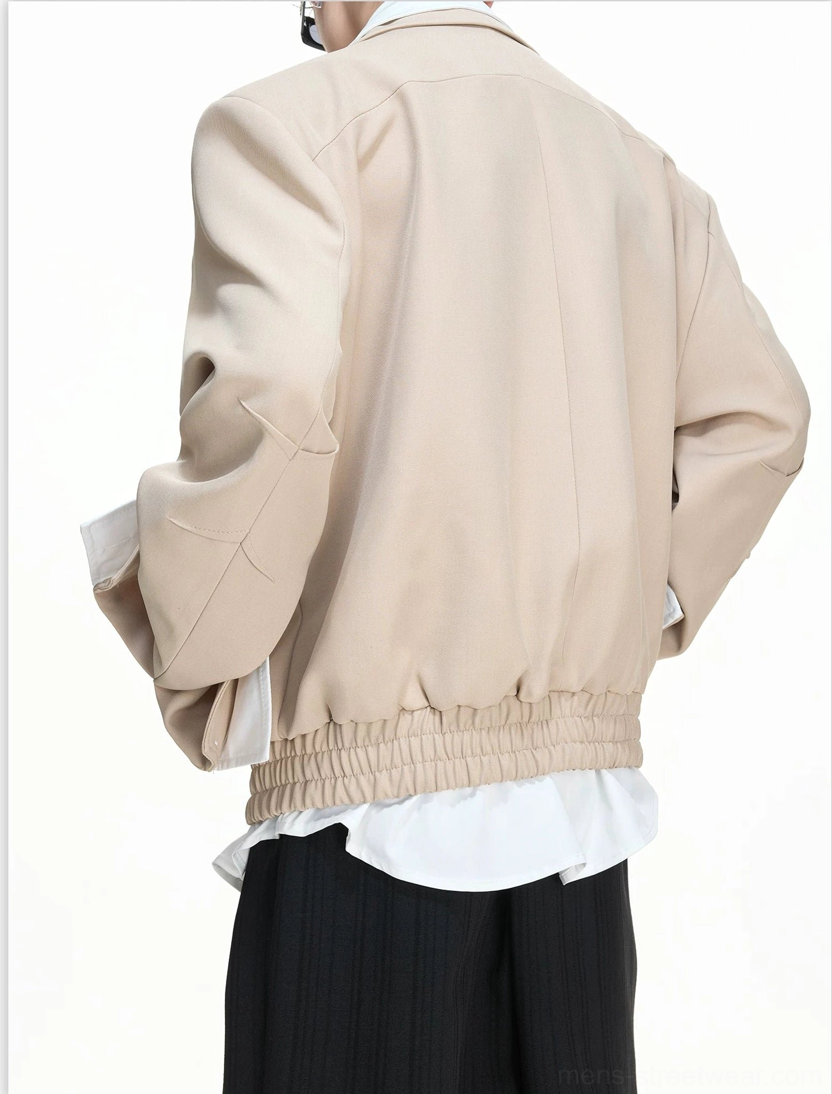 Back view of the khaki false-layer blouson showing its elasticated waist hem, layered shirt tail, and sleeve finish