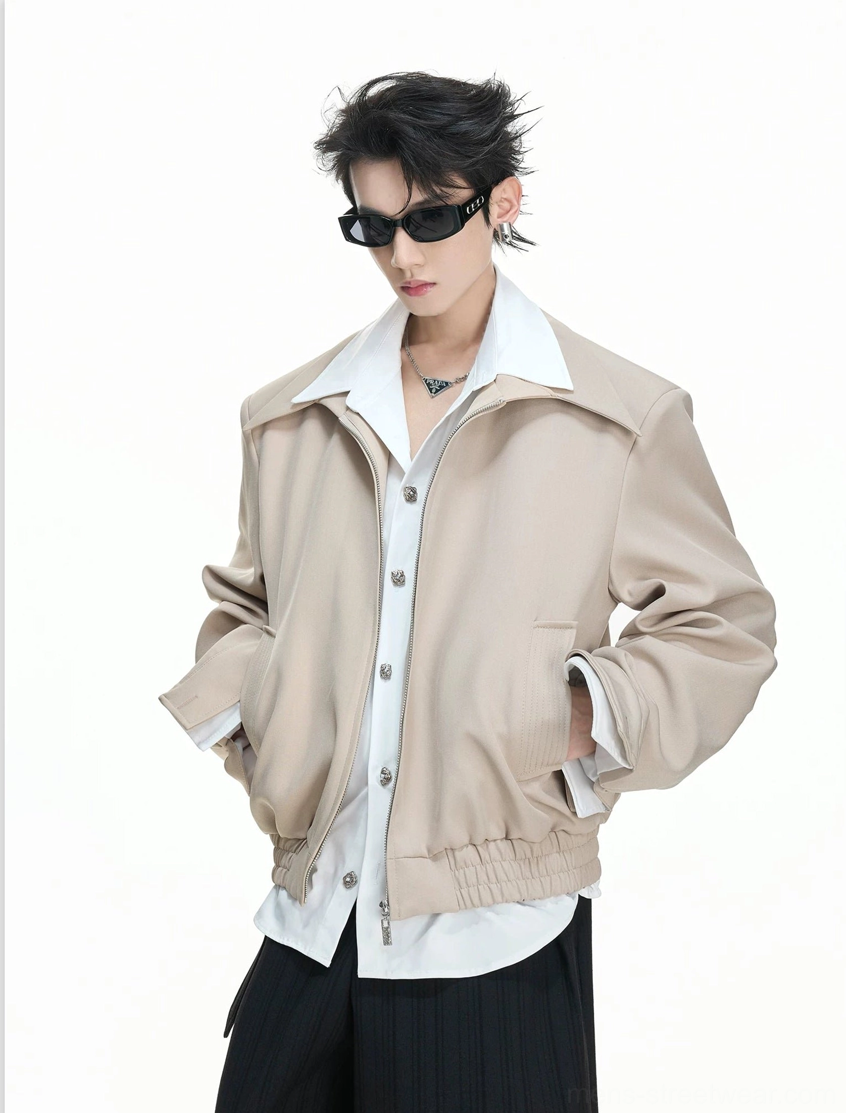 Model wearing a khaki false-layer zip blouson with exposed shirt collar and hem and hands in jacket pockets