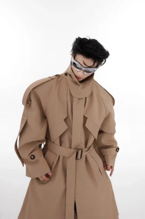Front view of khaki oversized shoulder pad trench coat featuring decorative shoulder straps, hidden front placket, high collar, and adjustable waist belt