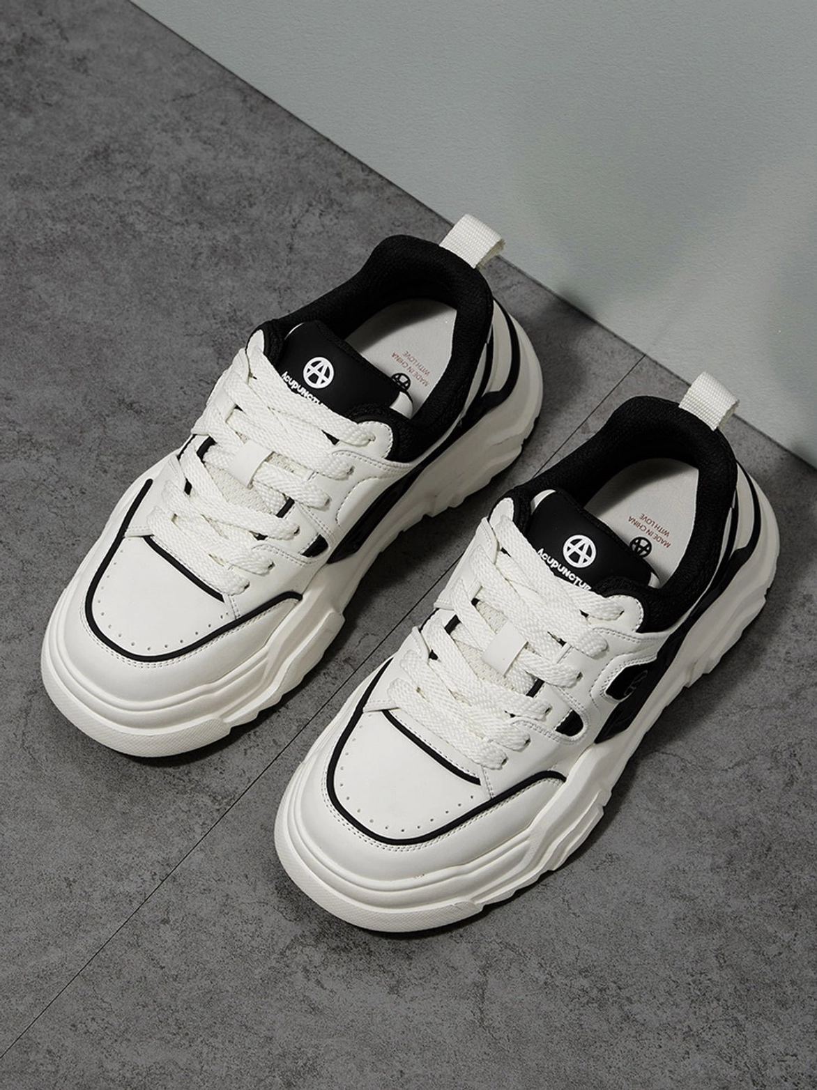 Khaki chunky platform sneakers placed oblique overhead view on dark gray cement background showing geometric cutout side panels detail