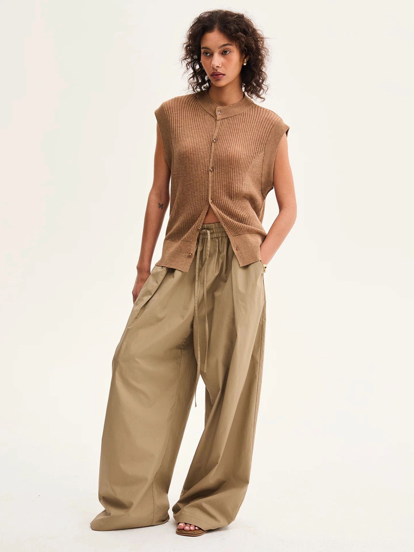 Khaki relaxed wide-leg cotton pants shown in a three-quarter view with pleated drawstring waist, oversized leg opening, and modern layered streetwear styling