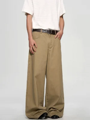 Front full-body view of khaki ultra-wide leg chino trousers styled with a striped white tee black leather belt and loafers