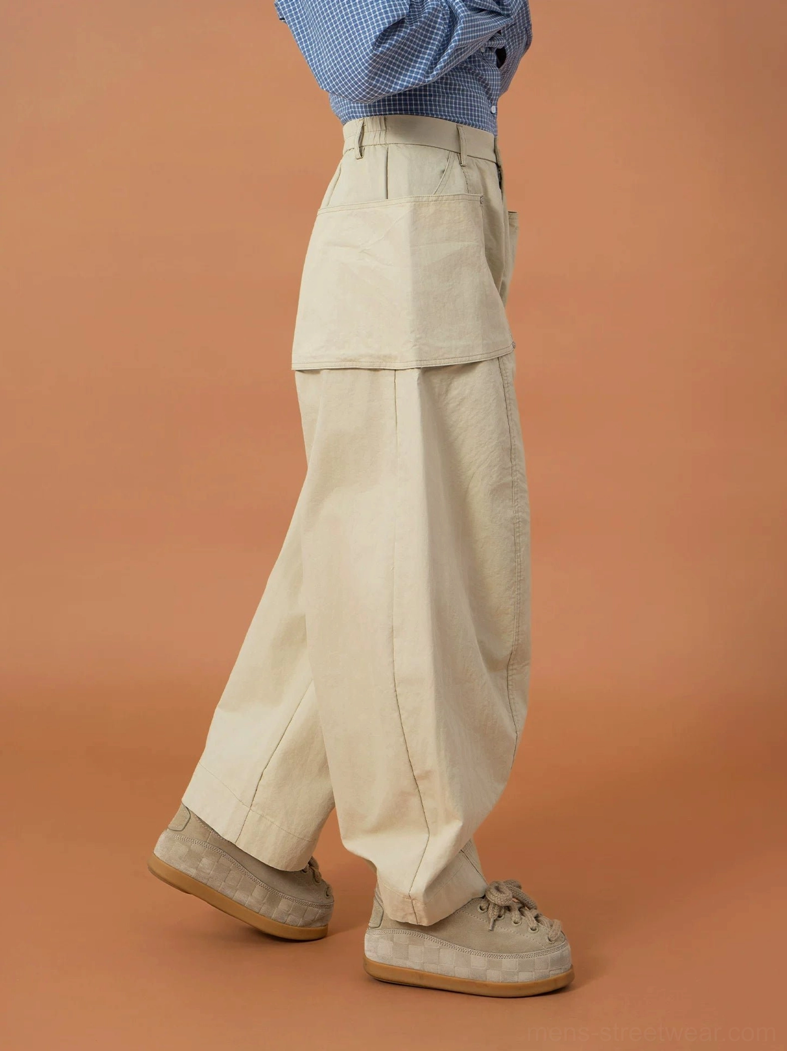 Side view of khaki oversized utility pants with a visible side patch pocket, textured cotton-blend fabric, and wide balloon legs