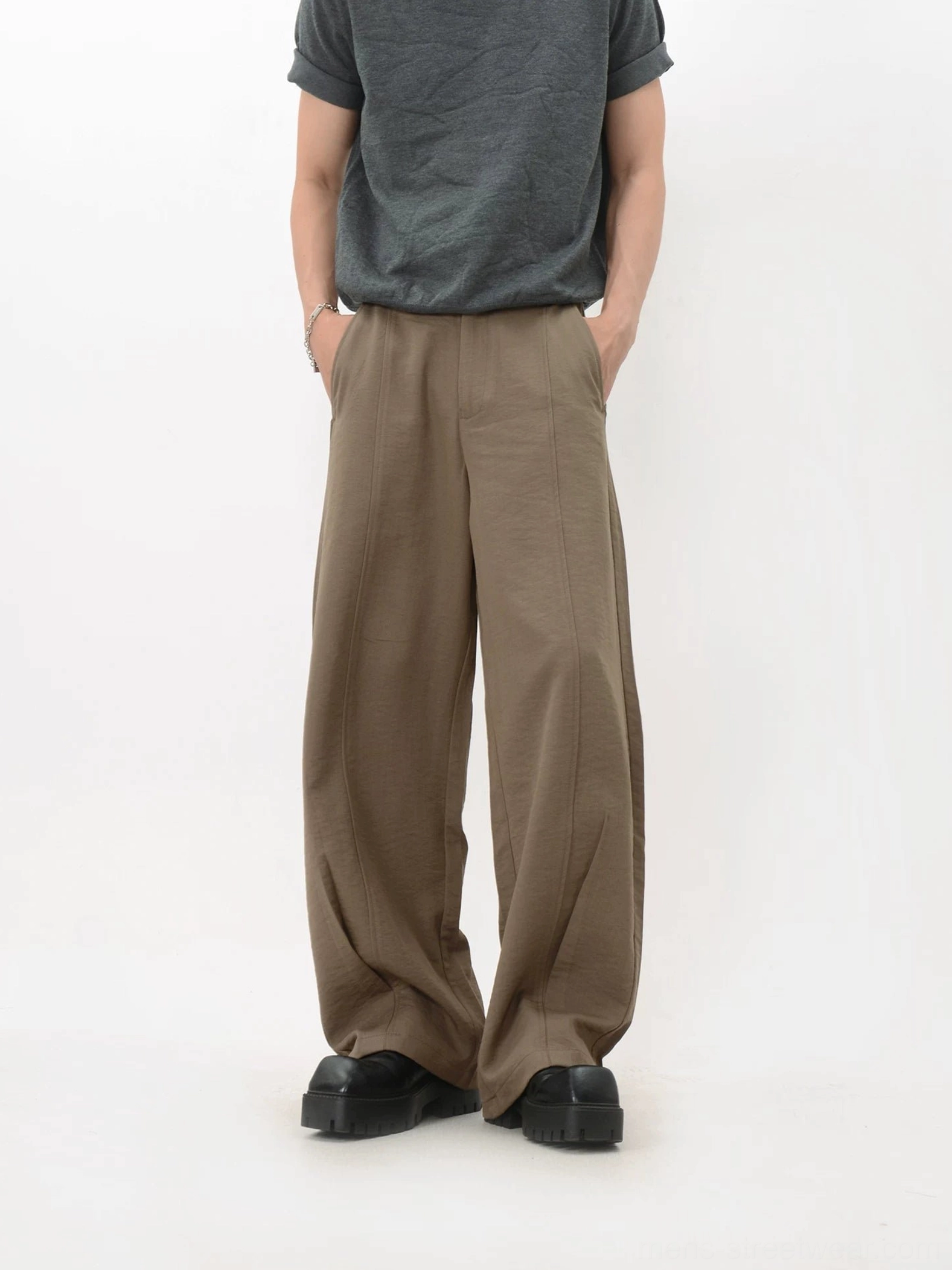 Front view of khaki wide-leg trousers with both hands in the side pockets, neat stitching, long legs, and casual tailored fit
