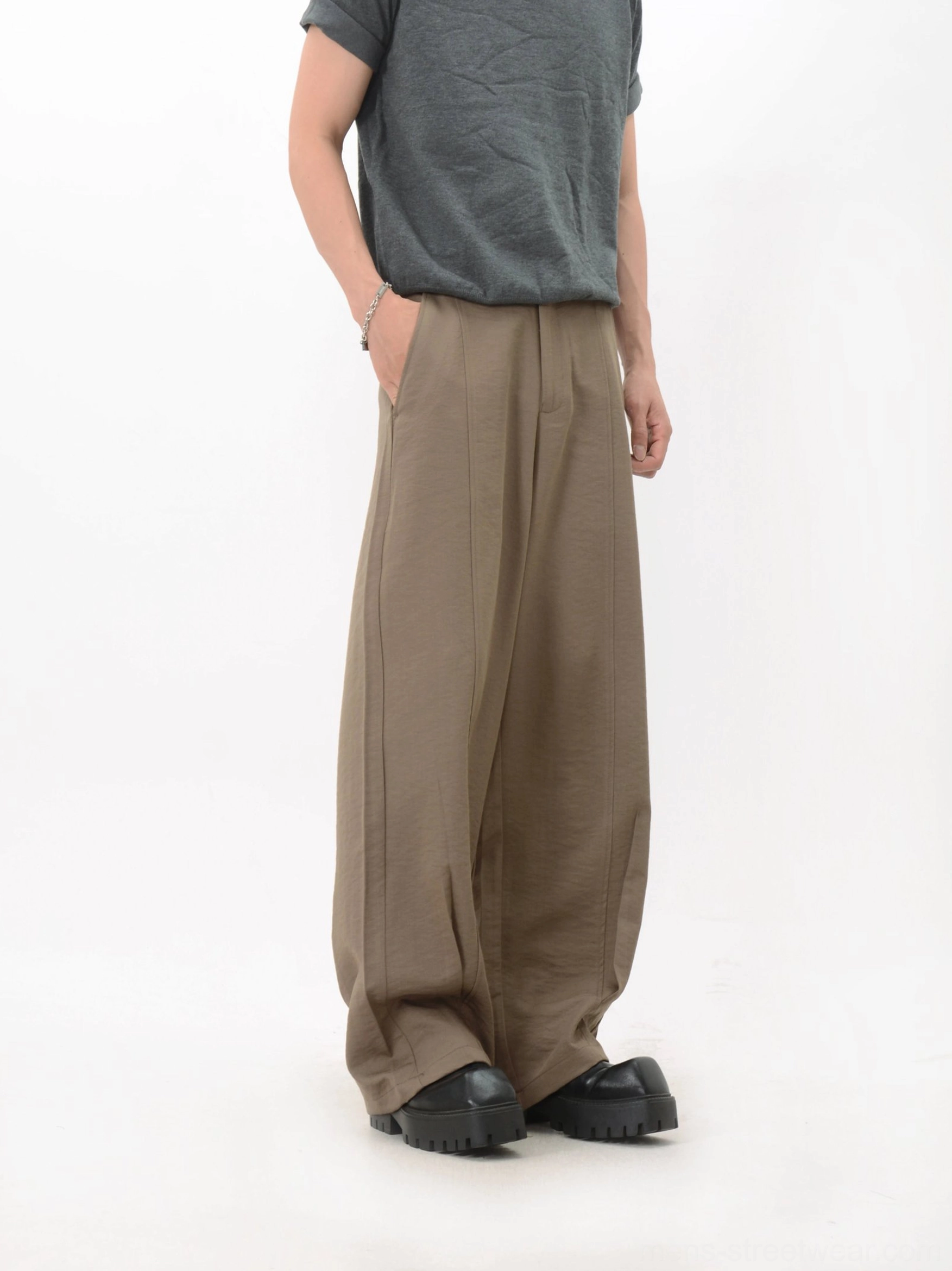 Side view of khaki full-length wide-leg trousers with front pleats, soft drape, wide hem, and relaxed contemporary streetwear shape