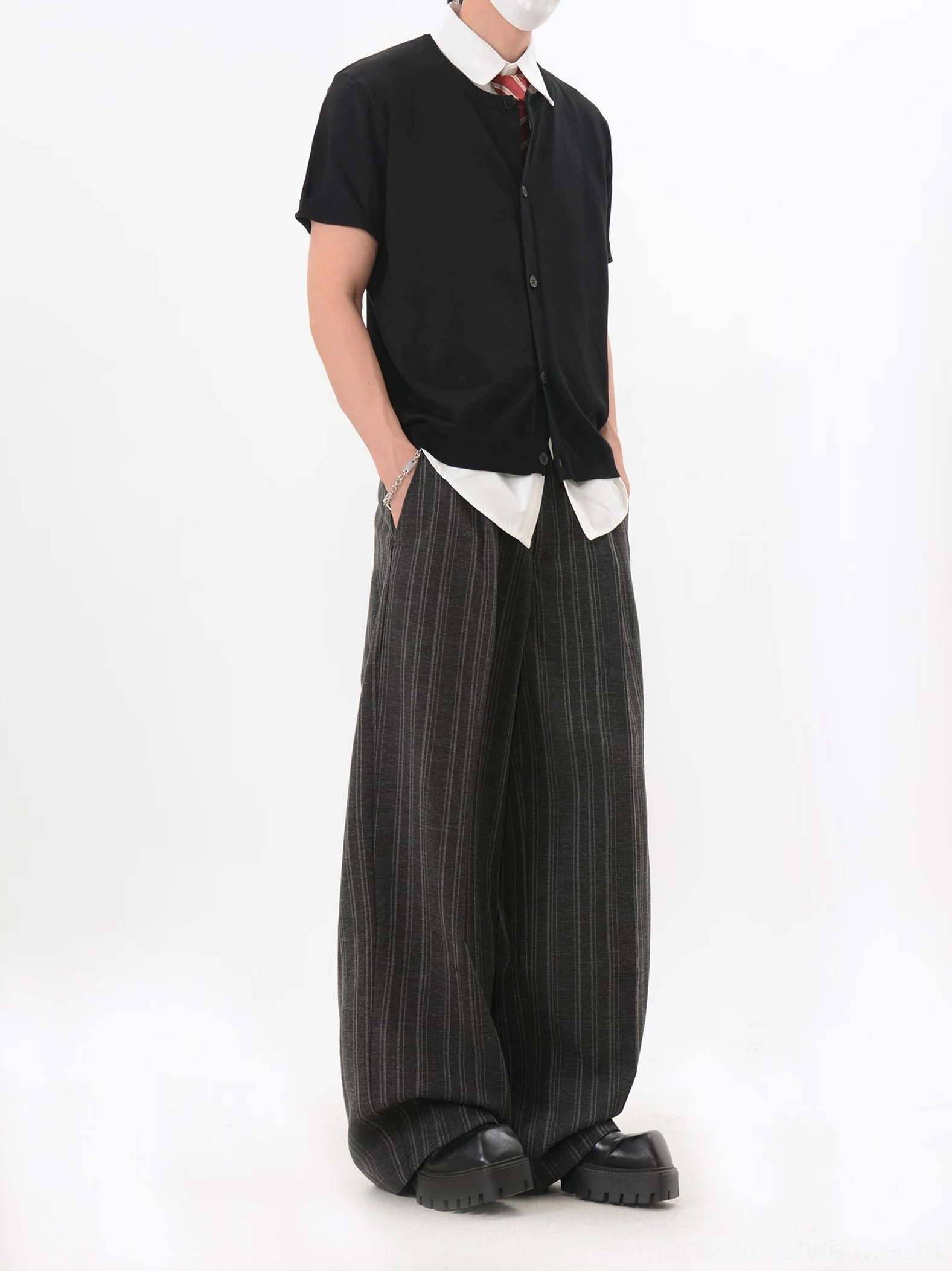Side three-quarter view of black short sleeve V-neck knit cardigan with layered shirt hem and wide-leg black pants