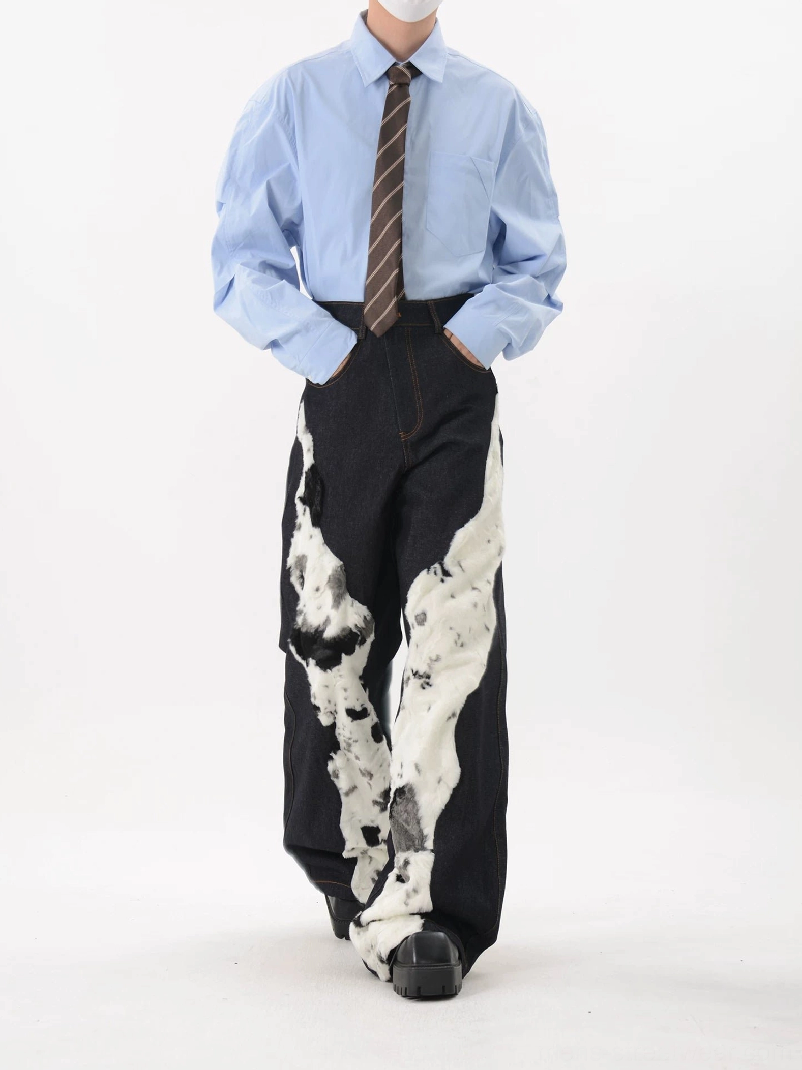 Three-quarter view of Korean streetwear cow pattern faux fur denim jeans with asymmetrical leg panels and loose fit