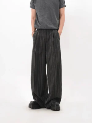 Front three-quarter view of black pinstripe wide-leg trousers styled with a grey tee and black platform shoes