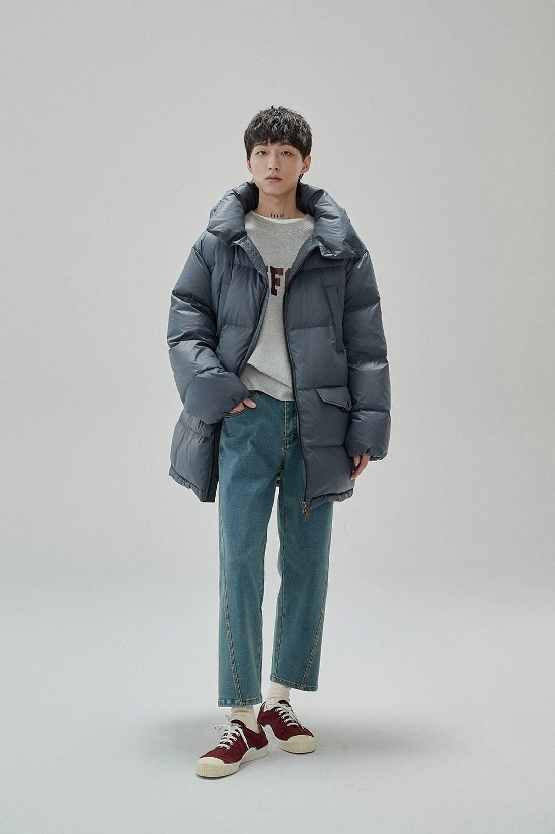 Full-body Korean streetwear outfit with gray UNIFORM sweatshirt dark puffer jacket and blue jeans