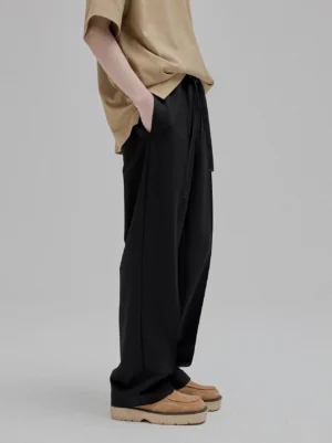 Side view partial lower body of black lace-up straight leg tapered trousers with smooth drapey viscose fabric high-waisted silhouette