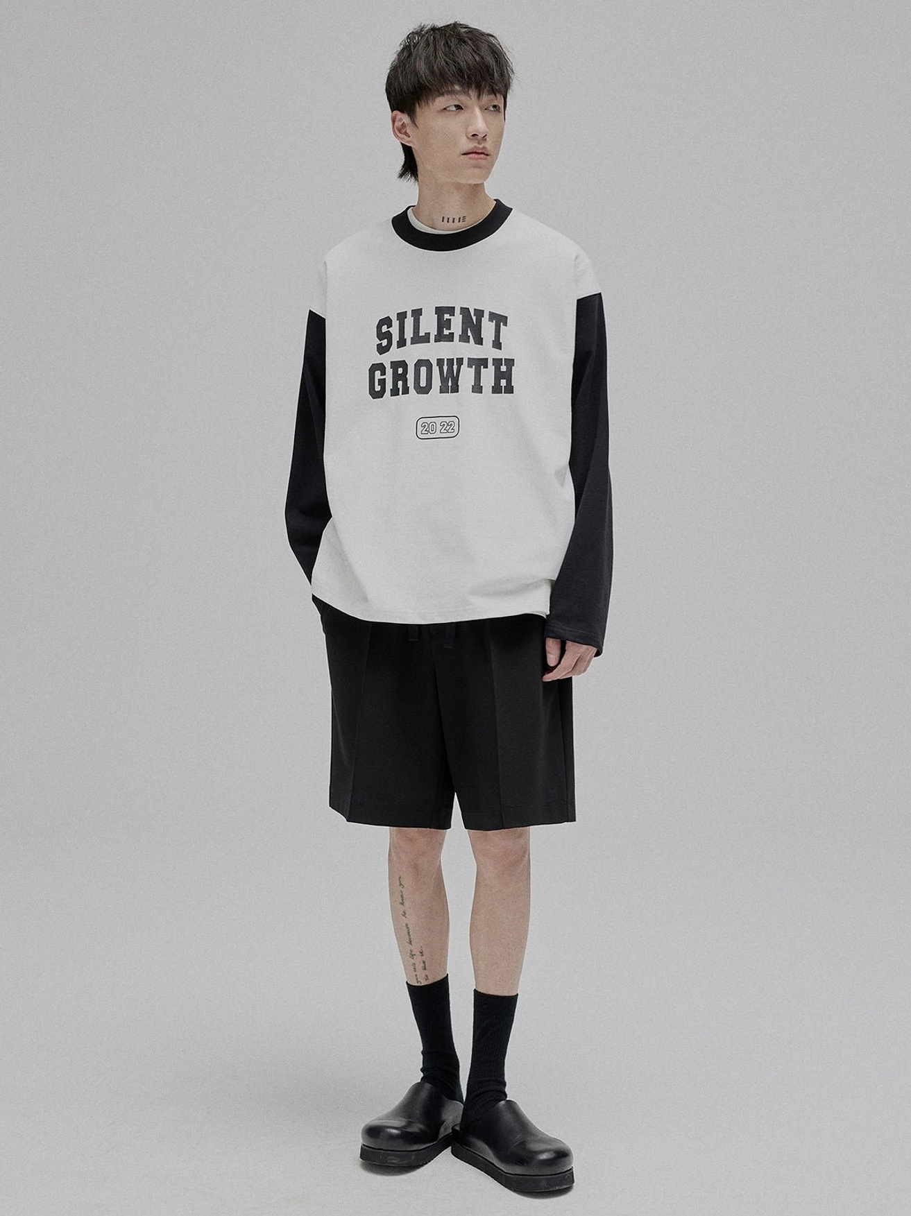Full body front view male model wearing lace-up straight leg casual shorts with colorblock sweatshirt minimalist streetwear styling