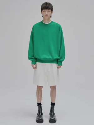 Male model wearing oversized lace-up straight leg streetwear shorts in neutral tone with drop shoulder sweatshirt full body front view studio