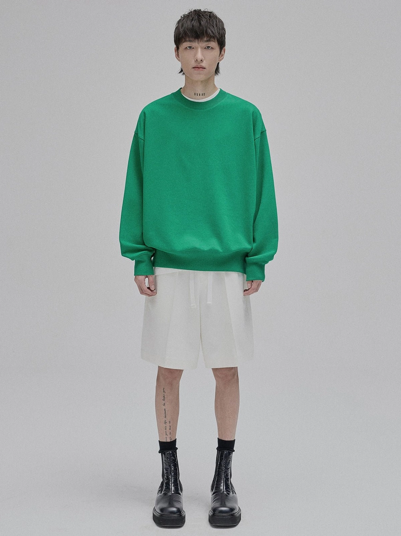 Male model wearing oversized lace-up straight leg streetwear shorts in neutral tone with drop shoulder sweatshirt full body front view studio