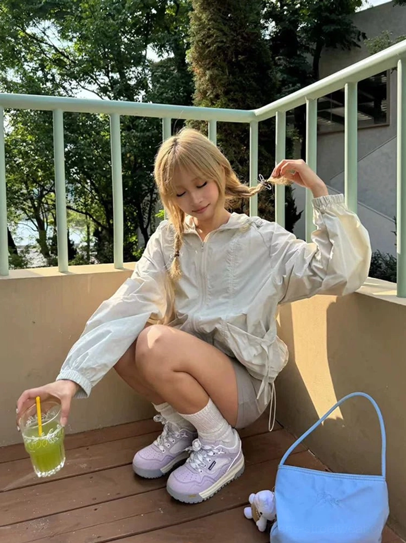 Model wearing lavender retro runner sneakers with white crew socks blue shoulder bag and relaxed Korean streetwear outfit
