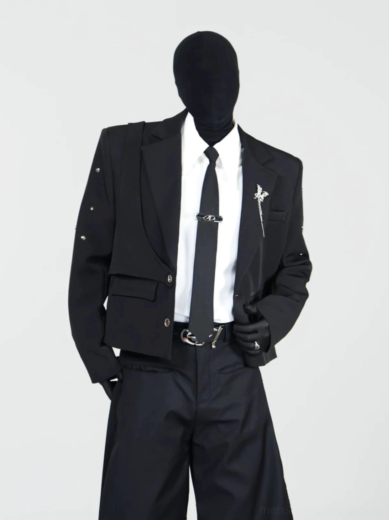 Three-quarter view of a layered black cropped blazer with metal tie clip, decorative brooch, wide-leg trousers, and avant-garde Seoul streetwear styling