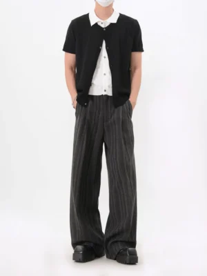 Full body view of black short sleeve layered knit cardigan shirt styled with striped wide-leg trousers and leather shoes
