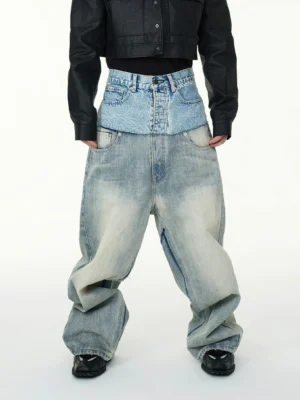 Front full body view of layered two tone high waisted baggy jeans in faded blue denim styled with a black cropped jacket and sneakers