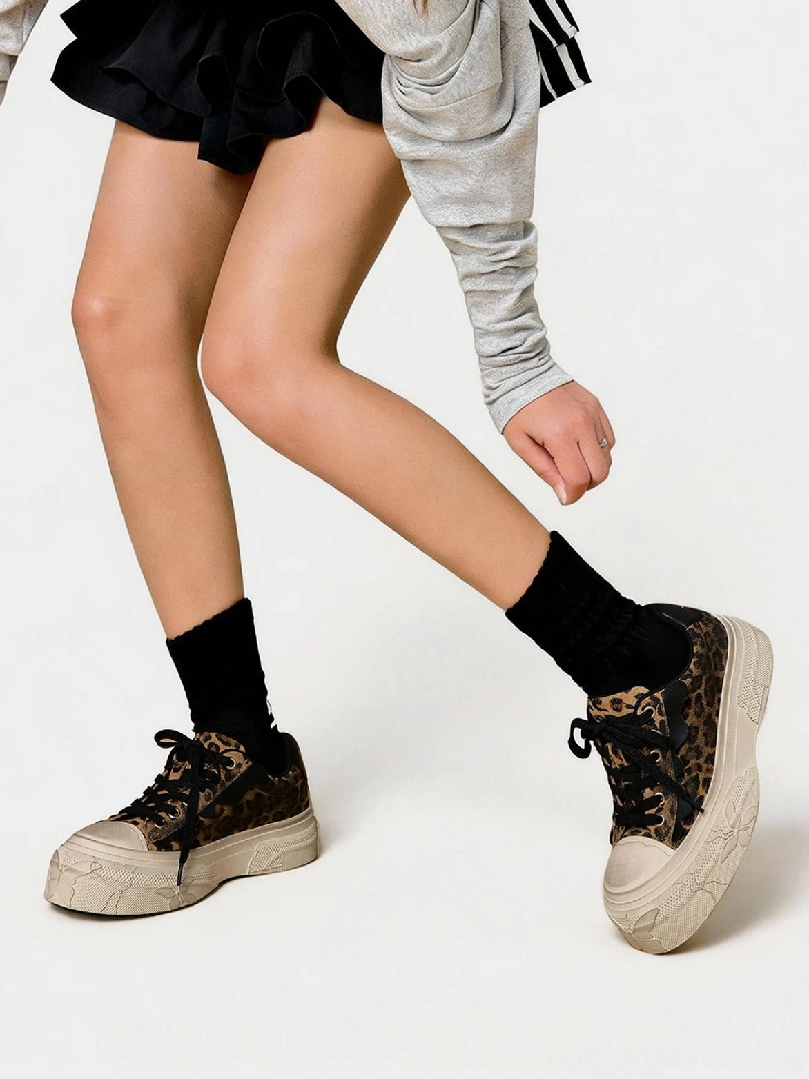 Leopard distressed platform canvas sneakers styled with black crew socks grey top and ruffled mini skirt in streetwear outfit
