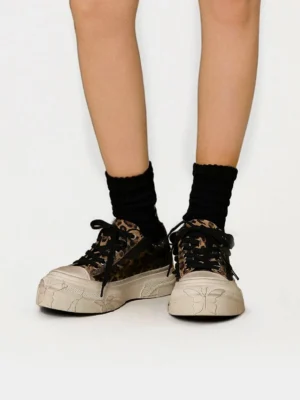 Front low angle view of leopard print platform sneakers worn with black crew socks showing distressed toe caps and thick soles