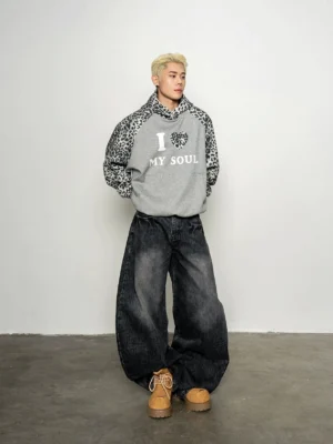 Front full-body view of oversized grey streetwear hoodie with leopard print raglan sleeves, leopard hood, and I Love My Soul chest graphic styled with baggy black jeans and work boots