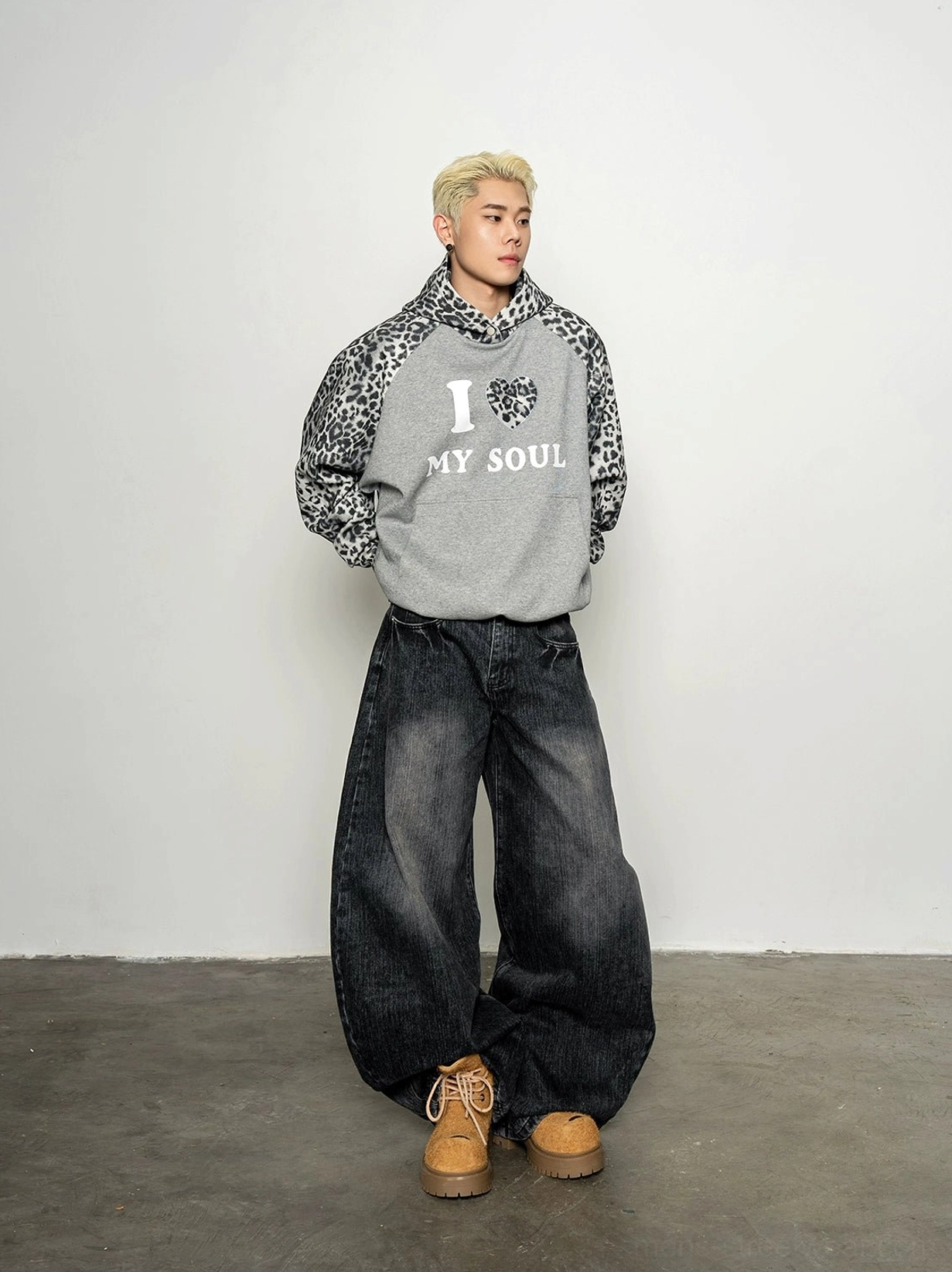 Front full-body view of oversized grey streetwear hoodie with leopard print raglan sleeves, leopard hood, and I Love My Soul chest graphic styled with baggy black jeans and work boots