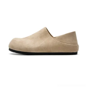 Light beige suede clogs with rounded closed toe, fold-down heel, and black rubber outsole shown in a clean studio product view