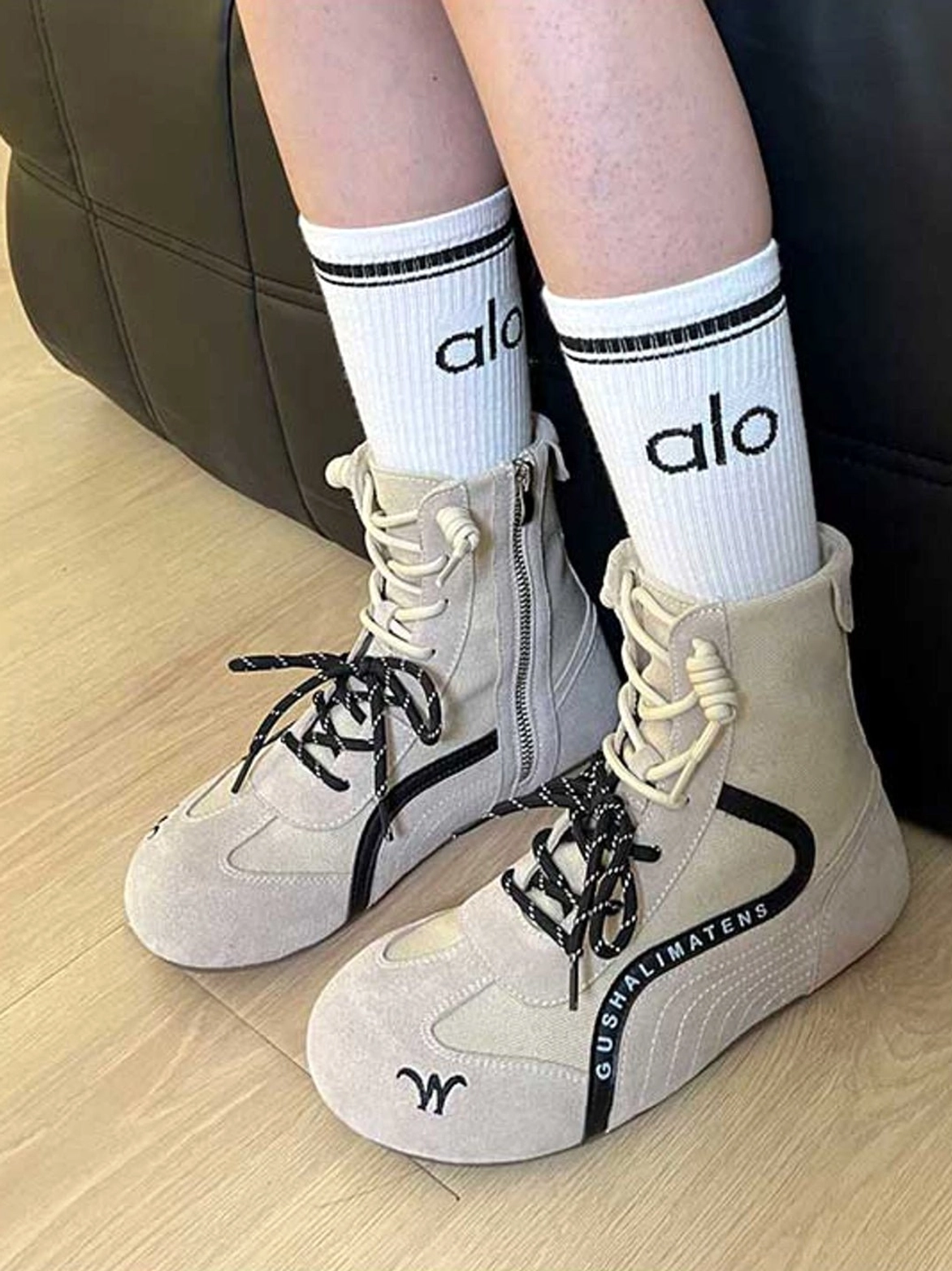 Light beige high-top suede racing boots worn with casual crew socks, showing lace-up and side zipper styling in a streetwear outfit