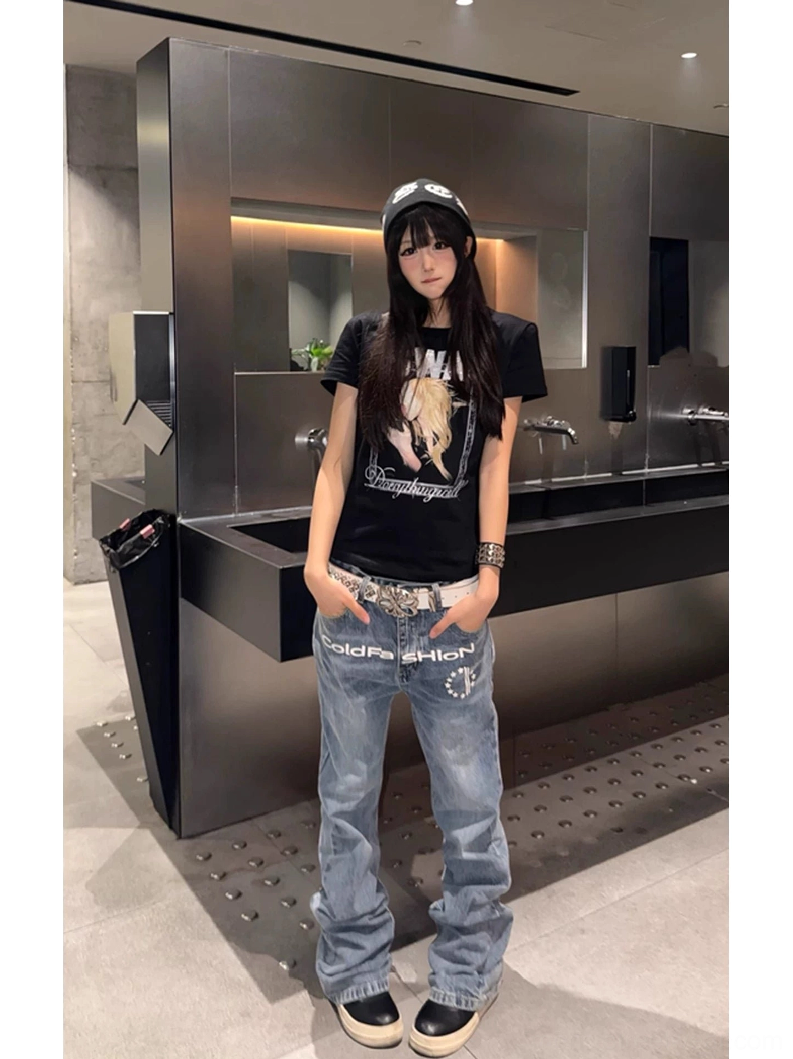 Female model styling light blue faded flare jeans with printed front emblem silver belt and wide legs in modern Korean streetwear fashion