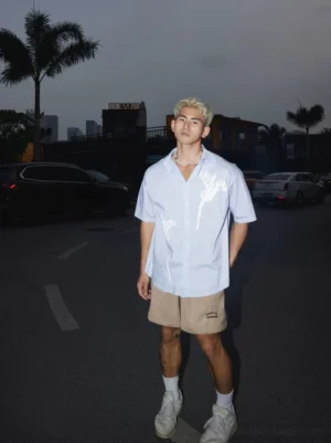 Front view of light blue white floral print short-sleeve button-up shirt styled with khaki shorts and white sneakers