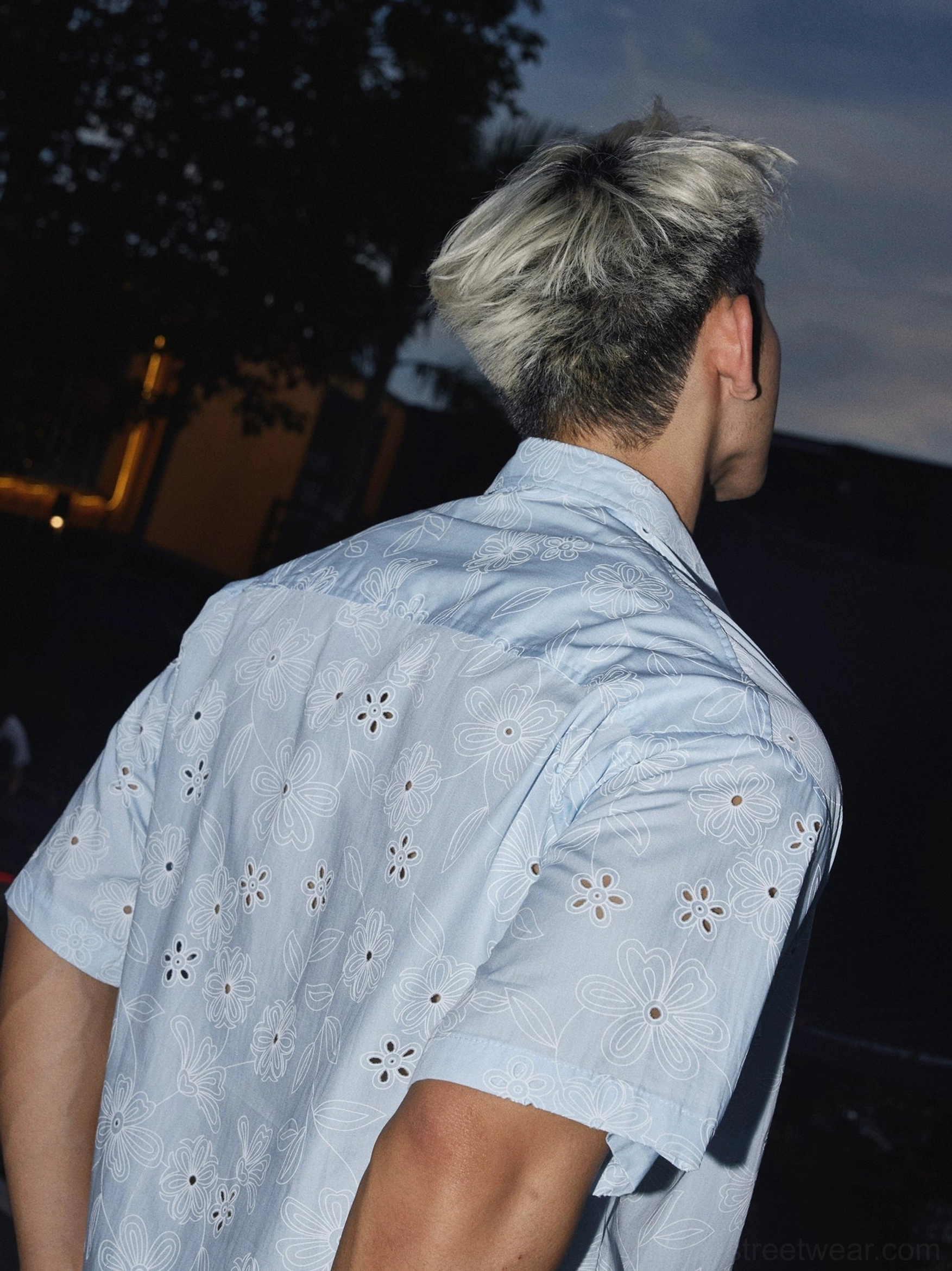 Back view of a light blue oversized floral eyelet short sleeve shirt showing the relaxed streetwear fit