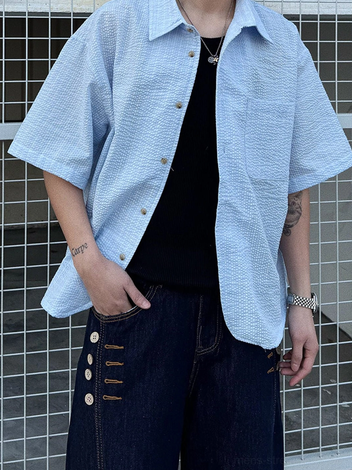 Light blue oversized textured short sleeve button shirt with seersucker-style finish layered over black T shirt