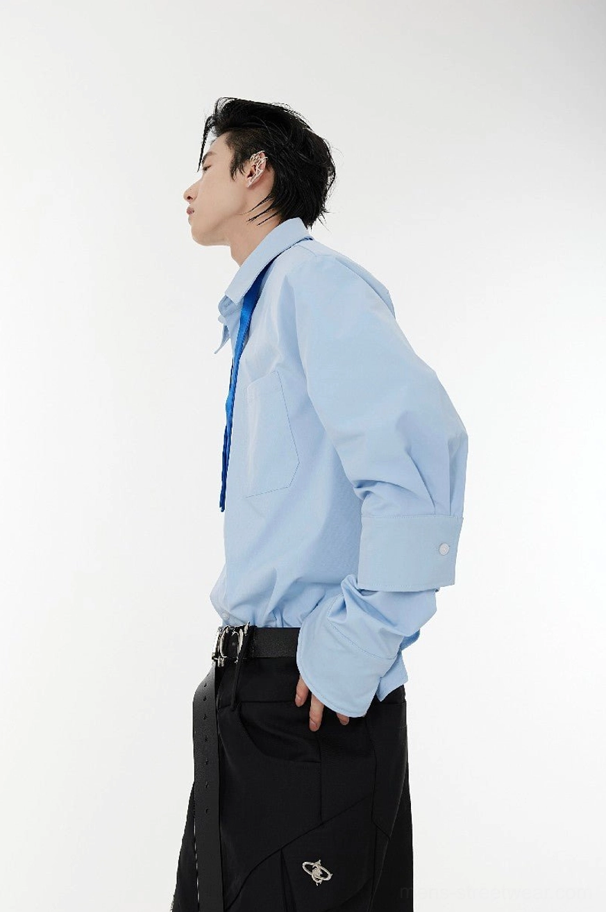 Light blue oversized tie-neck shoulder pad shirt side profile with button cuffs and relaxed Seoul streetwear fit